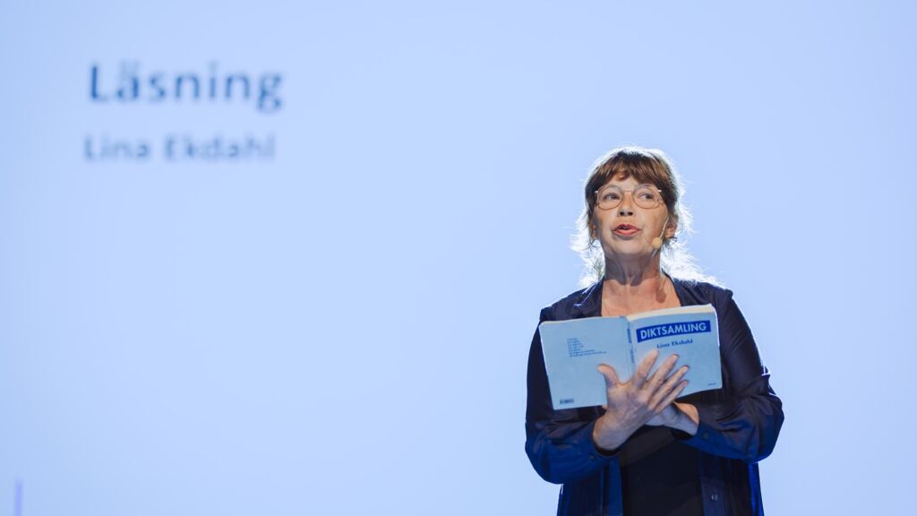 kvinna på scen som läser ur bok